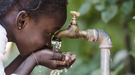 An African child with cupped hands drinking water from a tap